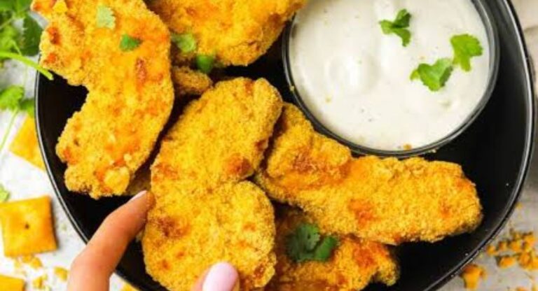 Crispy baked Cheez-It chicken tenders served hot with dipping sauce on a plate.