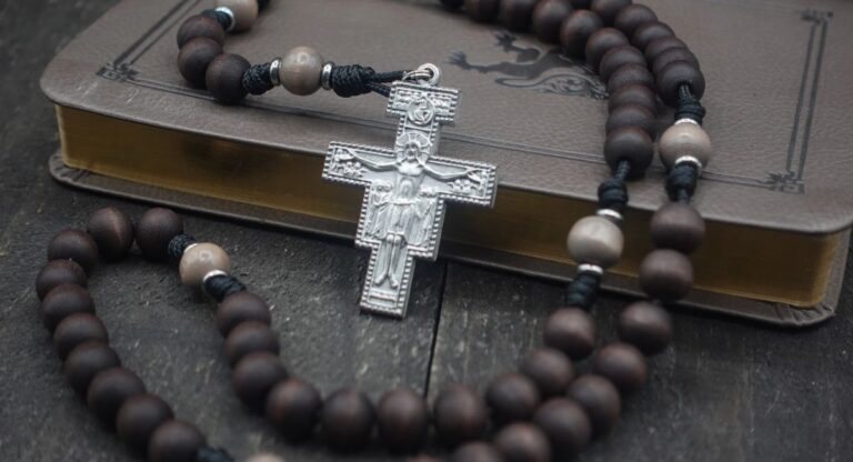 Saint Padre Pio praying before a crucifix with folded hands, symbolizing faith, healing, hope, and devotion to Jesus Christ.