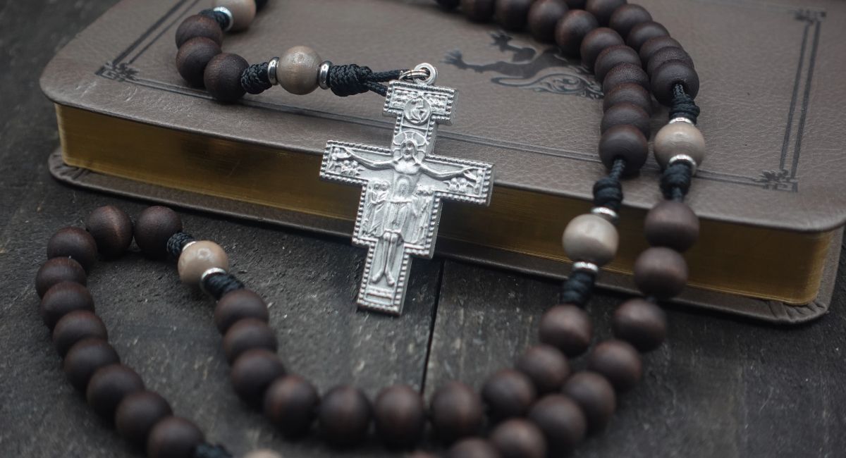 Saint Padre Pio praying before a crucifix with folded hands, symbolizing faith, healing, hope, and devotion to Jesus Christ.
